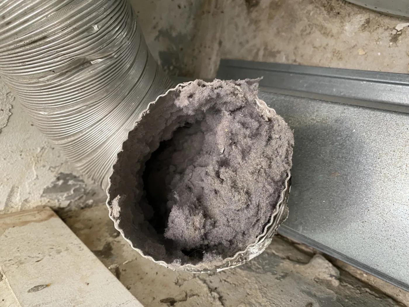 Dryer vent cleaning photo showing lint accumulation before removal.